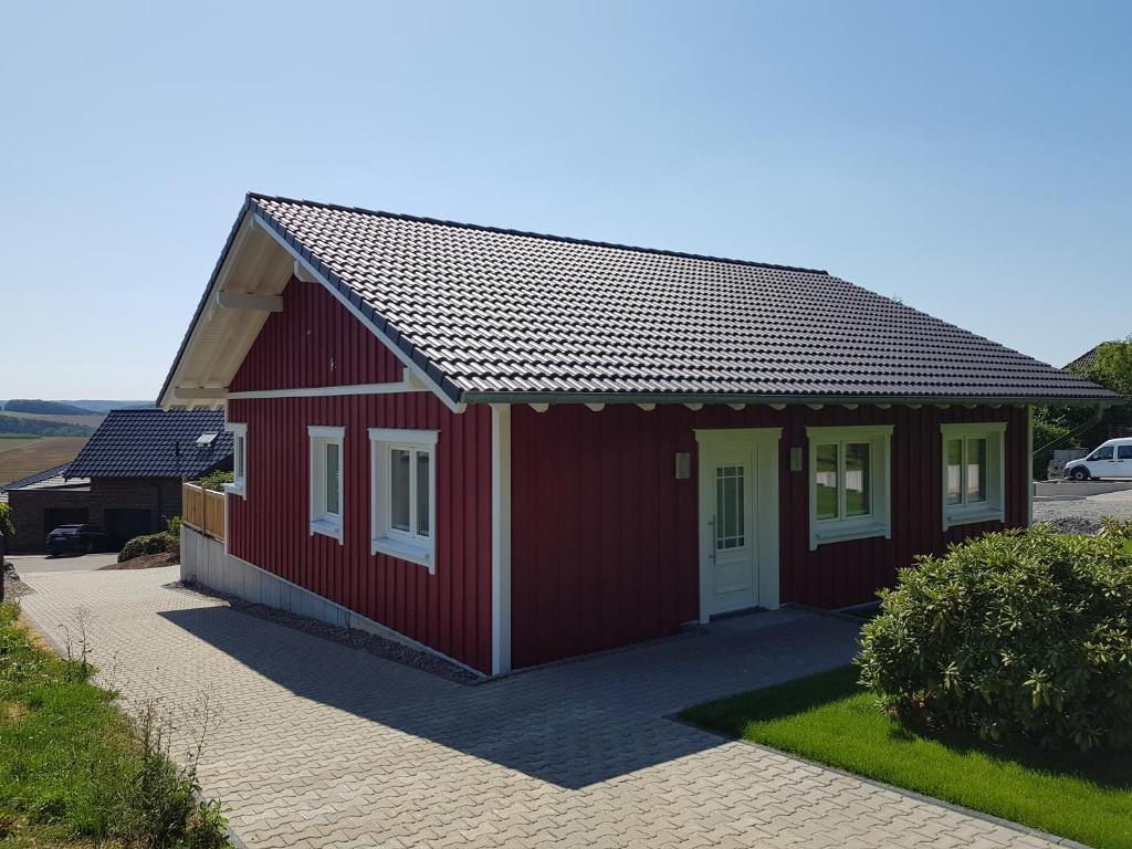 a red building with white doors on a driveway at Ferienhaus Löh in Kleinmaischeid