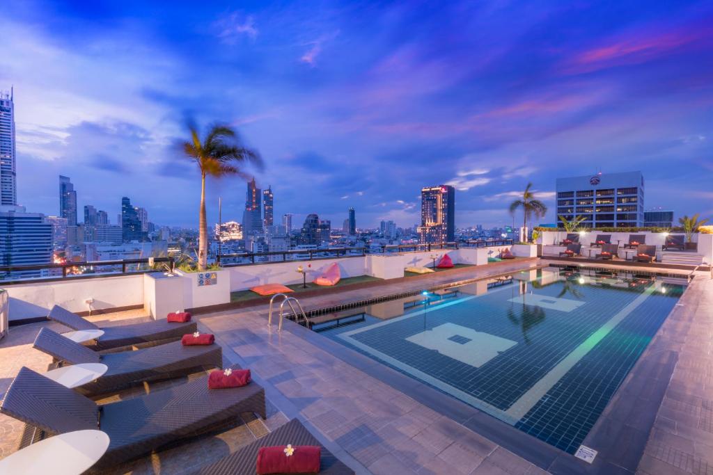 a swimming pool on top of a building with a city skyline at Furama Silom Hotel in Bangkok