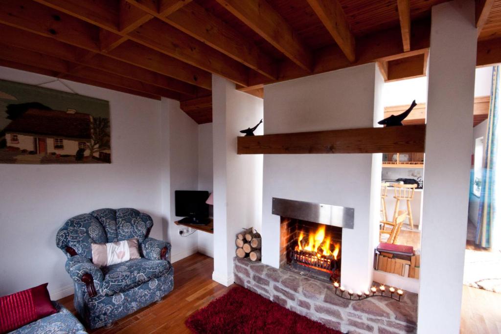 a living room with a fireplace and a chair at Achill Cottages in Achill Sound