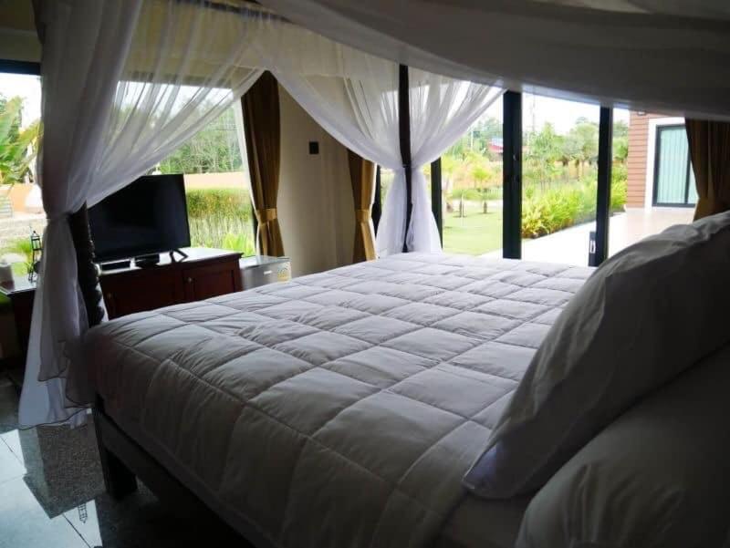 Tinna Resort في Ban Nong Mai Ngam: غرفة نوم بسرير كبير وتلفزيون