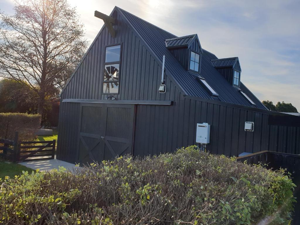 a black barn with a gambrel roof at Accommodation at Lakeside in Oamaru
