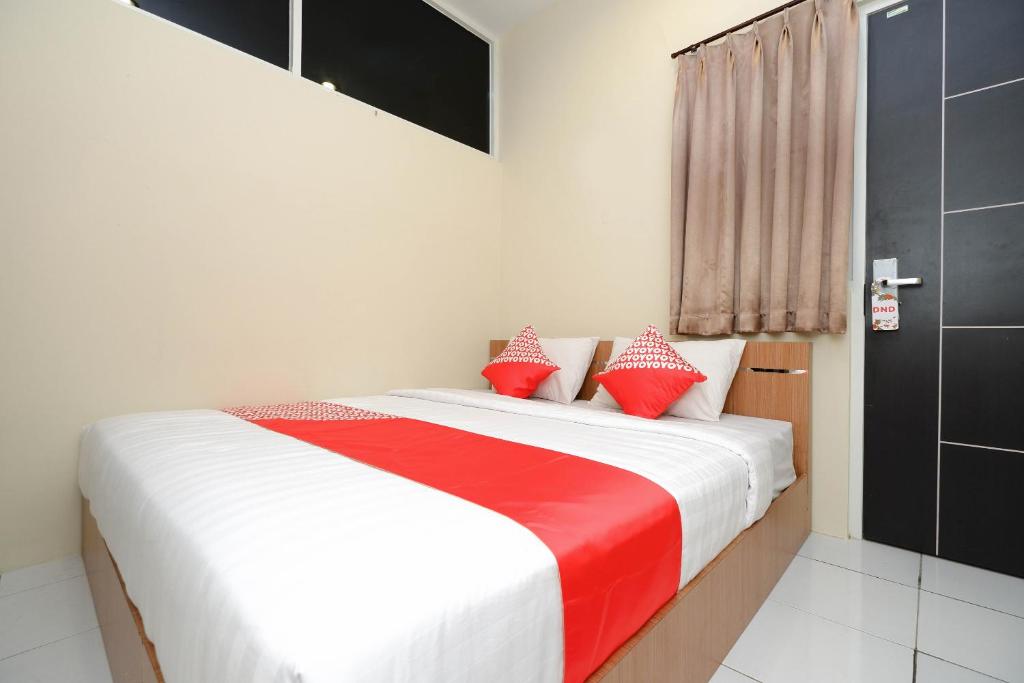 a bedroom with a bed with red and white pillows at OYO 1250 Unta Residence in Semarang