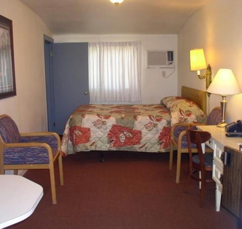 Habitación de hotel con cama, mesa y sillas en Hacienda Motel, en Alturas