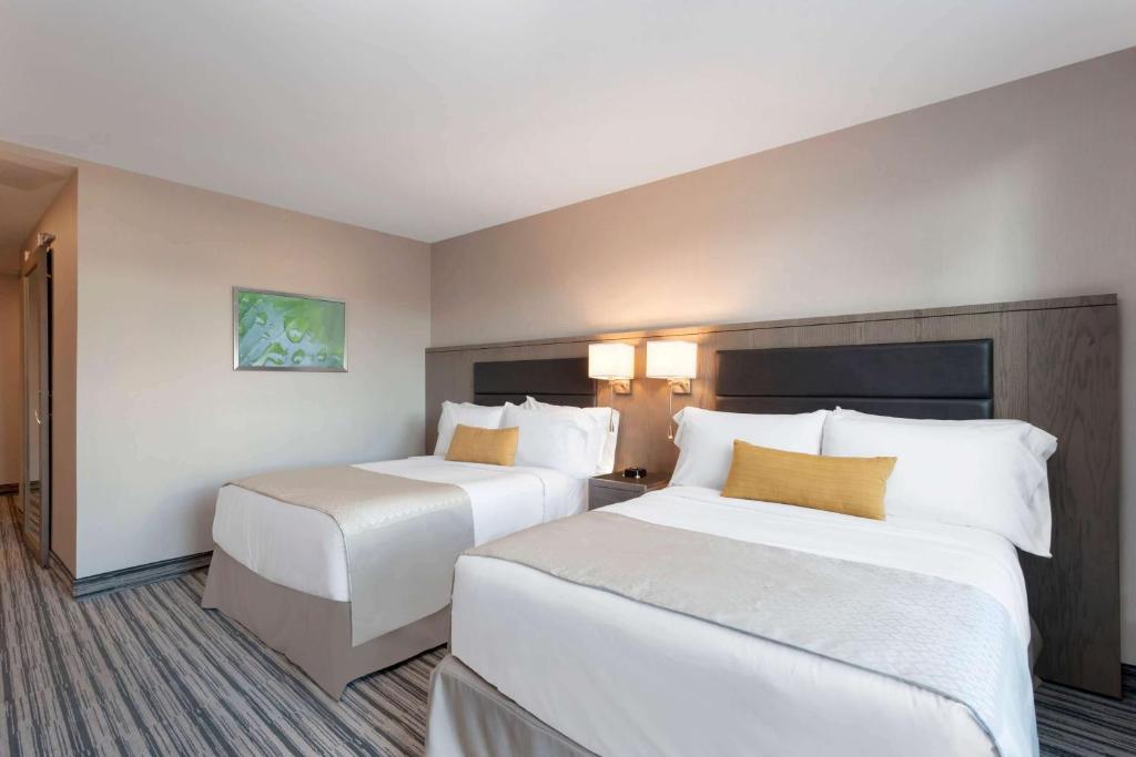 two beds in a hotel room with white and yellow pillows at Wyndham Garden LaGuardia South in Queens