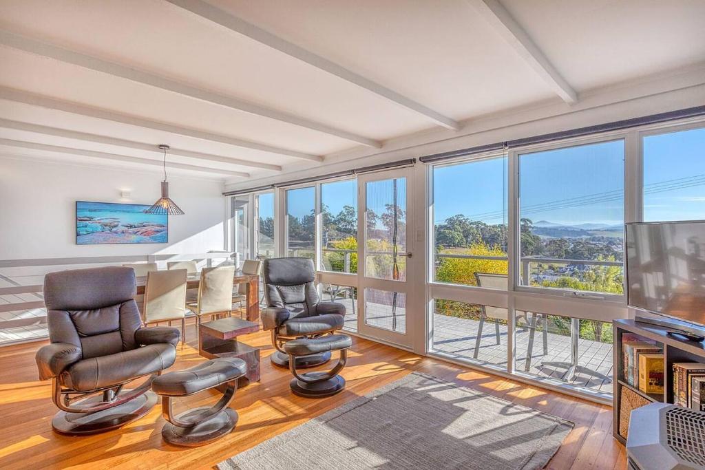 a living room with a table and chairs and windows at Mimosa Holiday House in St Helens