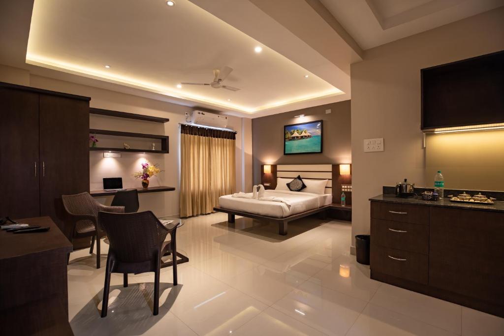 a hotel room with a bed and a table and chairs at Aadya Elite in Mysore