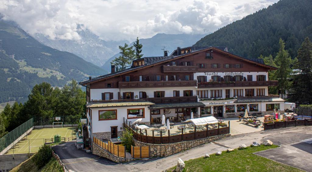 a large building on a hill with mountains in the background at Hotel Vallechiara in Bormio