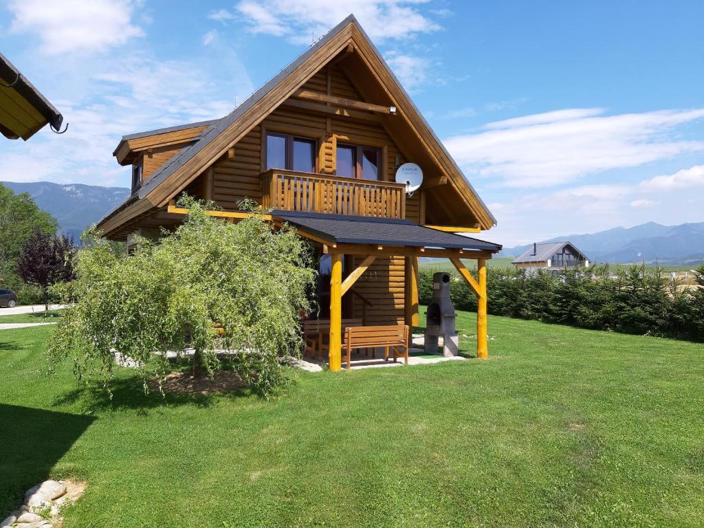 a log cabin with a balcony on a lawn at Chaty Rybárska Osada in Liptovská Sielnica