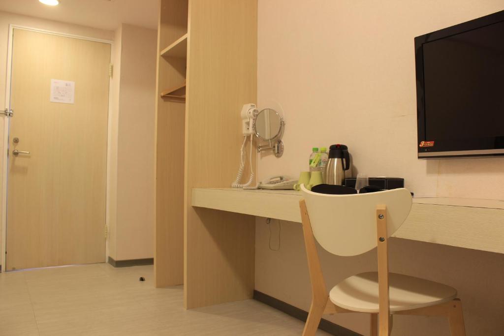 a room with a desk with a phone and a chair at Sunnyside Hotel in Kaohsiung