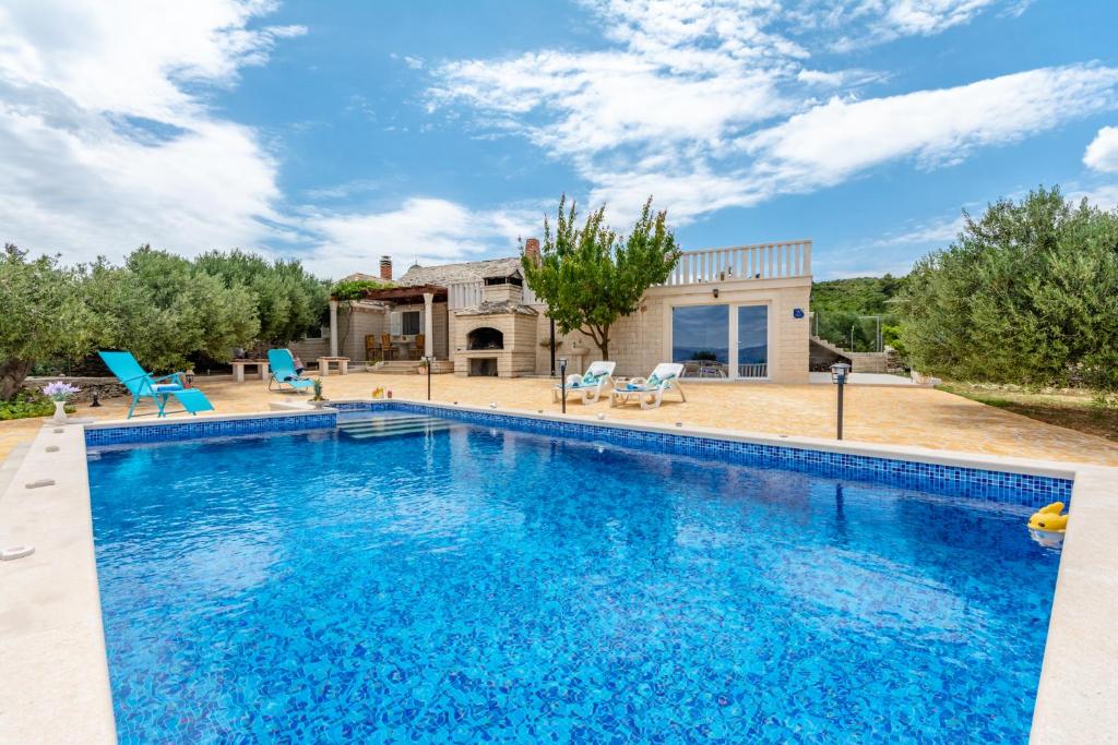 a large swimming pool in front of a house at Vila Maslinica in Pučišća