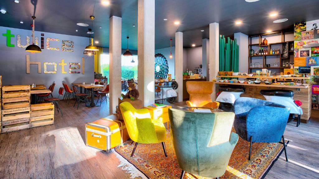 tinyTwice Hotel Wiesbaden في فيسبادن: مطعم فيه كراسي صفراء وزرقاء في الغرفة