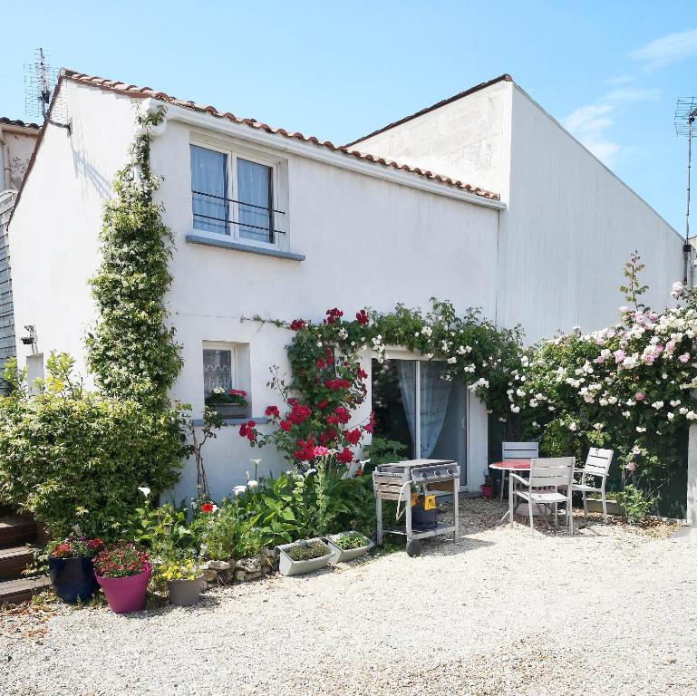 a white house with flowers and plants in front of it at au pied de l'Ile Oléron in Bourcefranc