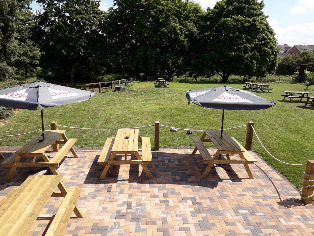 2 mesas de picnic con sombrillas en el patio en Newton Brewery Inn, en Middlewich