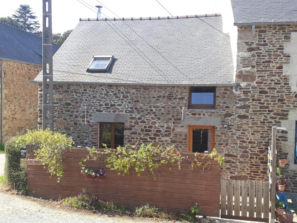 a brick house with a wooden fence in front of it at La Lyonnais in Pleslin-Trigavou