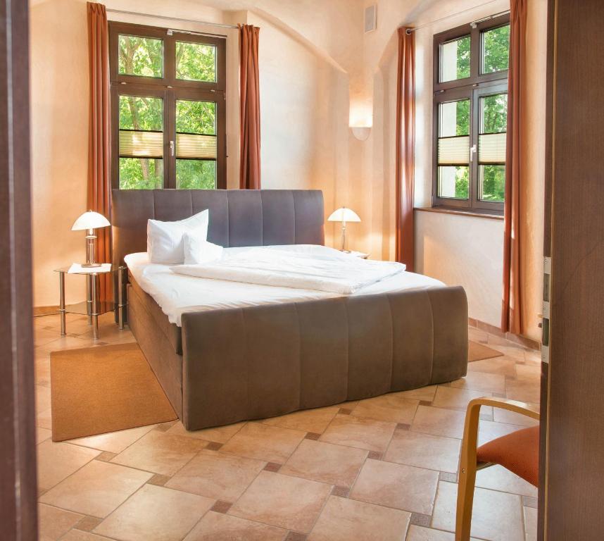ein großes Bett in einem Zimmer mit zwei Fenstern in der Unterkunft Hotel Alte Canzley in Lutherstadt Wittenberg