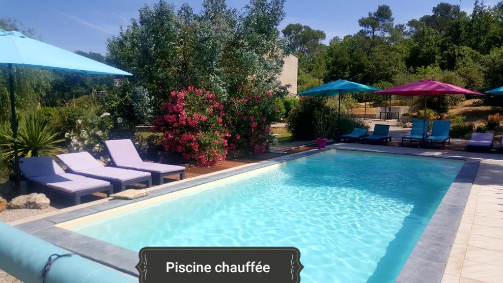 a swimming pool with chairs and umbrellas at La Bastide de l'Issole in Besse-sur-Issole