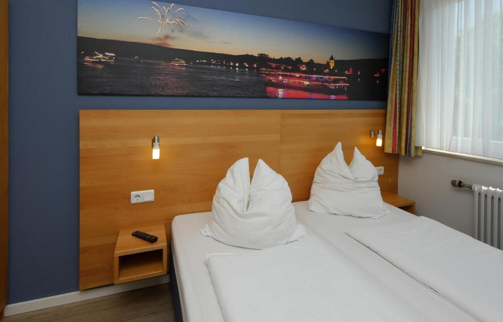 een hotelkamer met een bed met witte kussens bij Hotel Pinger in Remagen