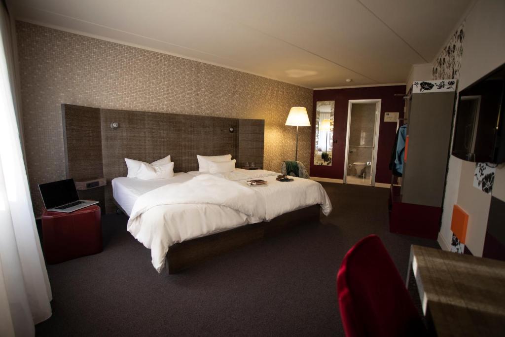 una camera d'albergo con un grande letto con lenzuola bianche di pentahotel Eisenach a Eisenach