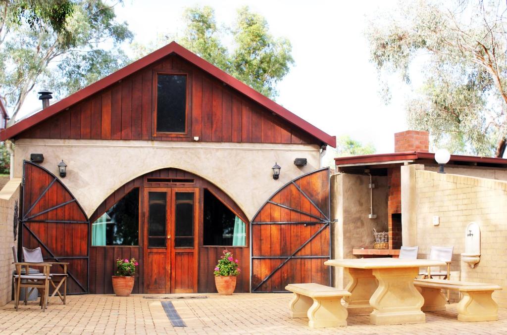 a barn with a wooden door and a picnic table at Outback Cellar & Country Cottage in Dubbo