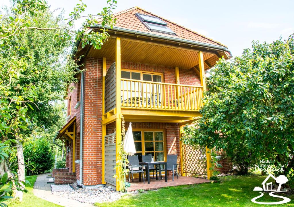 a house with a balcony and a table on a yard at Haus am Dorfteich Fehmarn in Dänschendorf