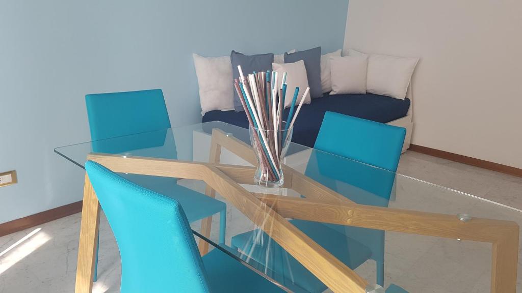 einen Glastisch mit blauen Stühlen und einem Sofa in der Unterkunft La Magnolia Apartments in Desenzano del Garda