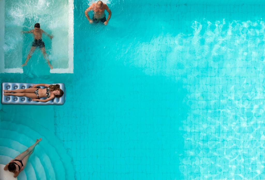 dos personas en el agua en una piscina en Hotel Poker, en Riccione