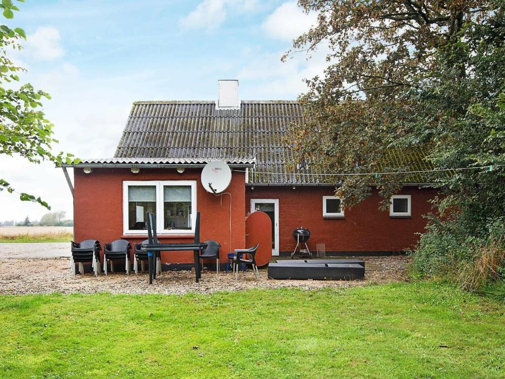 une maison rouge avec une table et des chaises devant elle dans l'établissement 12 person holiday home in Bredebro, à Bredebro