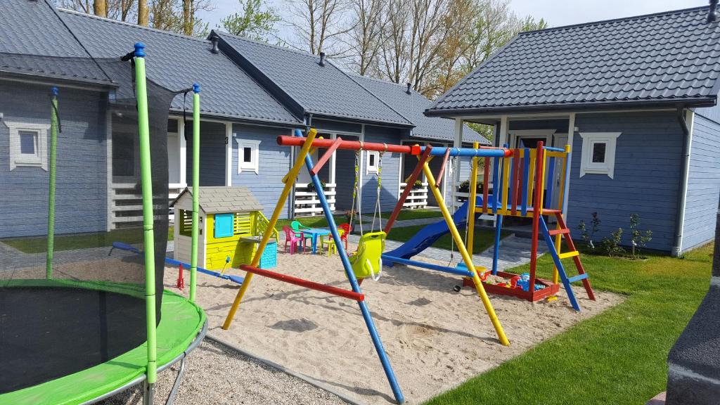 a playground in a yard with a house at Domki na Leśnej in Ustronie Morskie