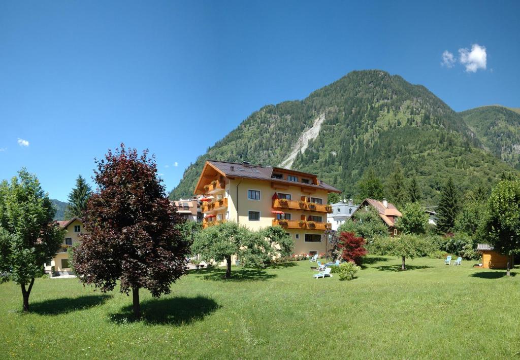 a building in a field with a mountain in the background at Appartements Monuth in Bad Hofgastein