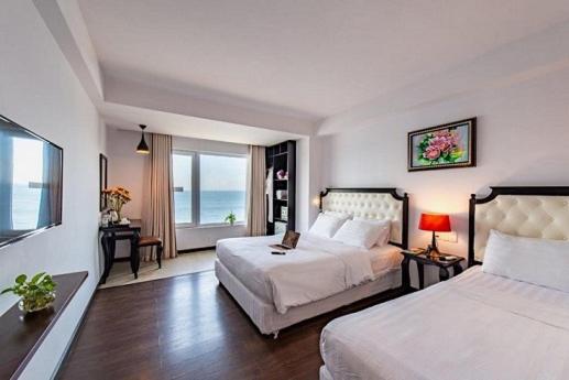 a bedroom with two beds and a view of the ocean at Bellevue Hotel in Nha Trang