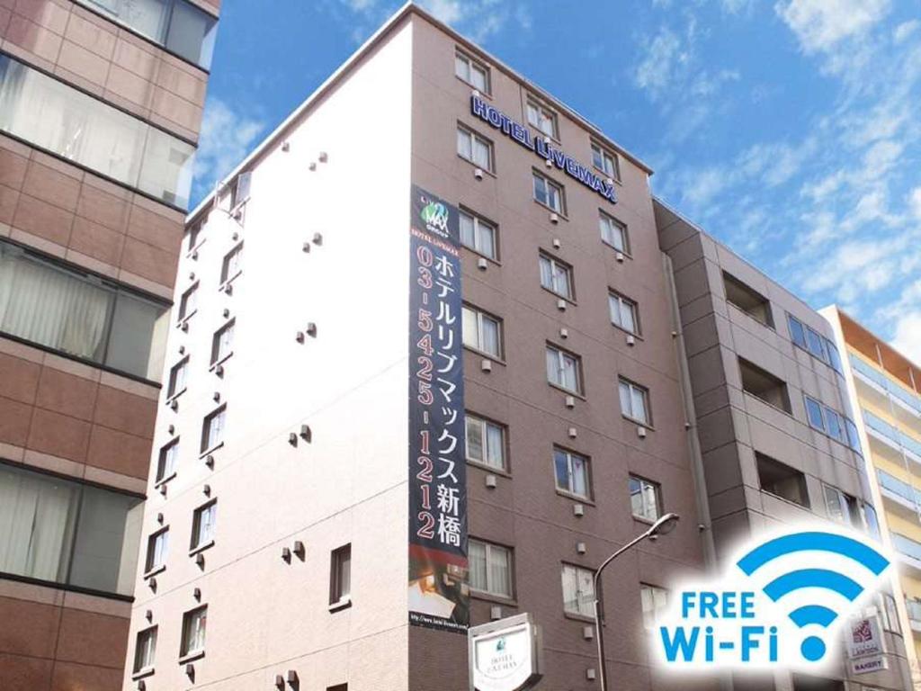 een gebouw met een gratis WiFi-bord ervoor bij HOTEL LiVEMAX BUDGET Shinbashi in Tokyo