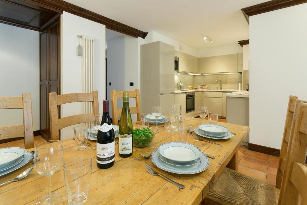 una mesa de madera con platos y botellas de vino. en APARTMENT KITSON - Alpes Travel - Chamonix - Sleeps 6 en Chamonix-Mont-Blanc