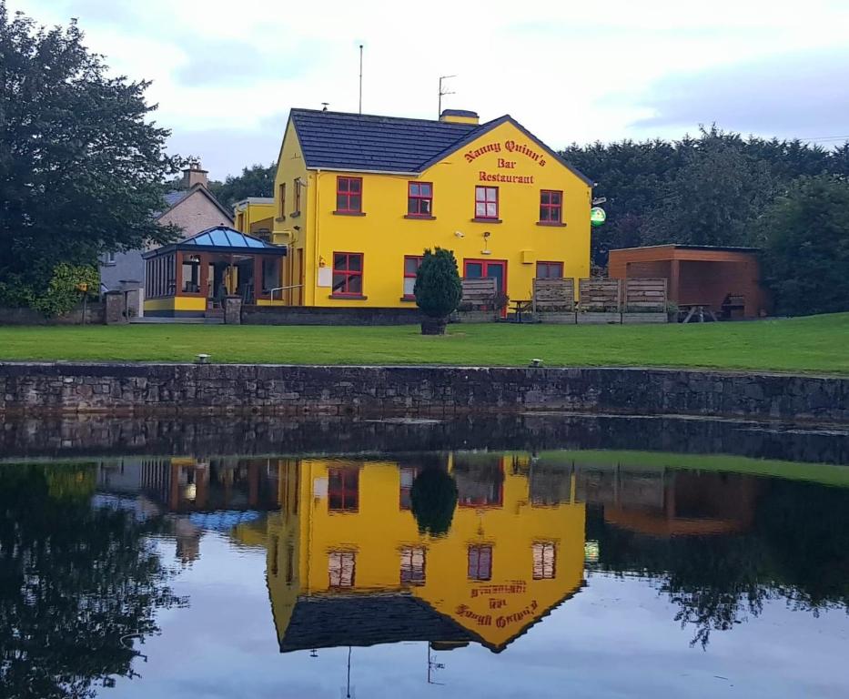 een geel huis wordt weerspiegeld in het water bij Nanny Quinn's Apartment in Killucan
