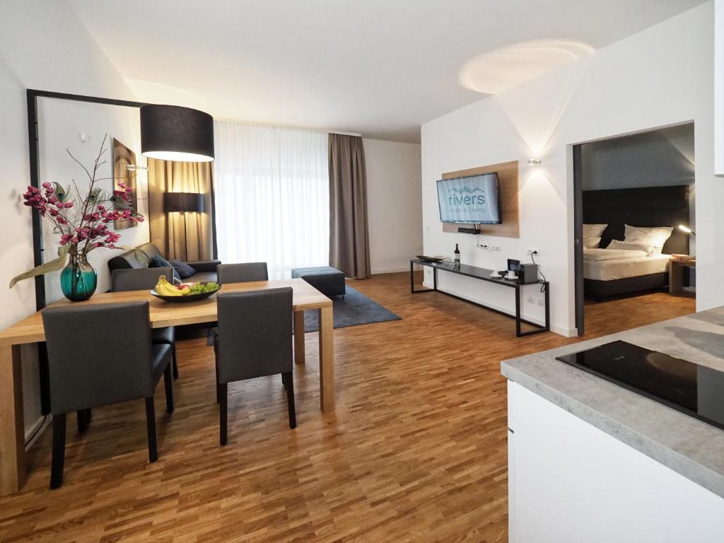 a living room with a table and a room with a bed at Rivers Passau in Passau