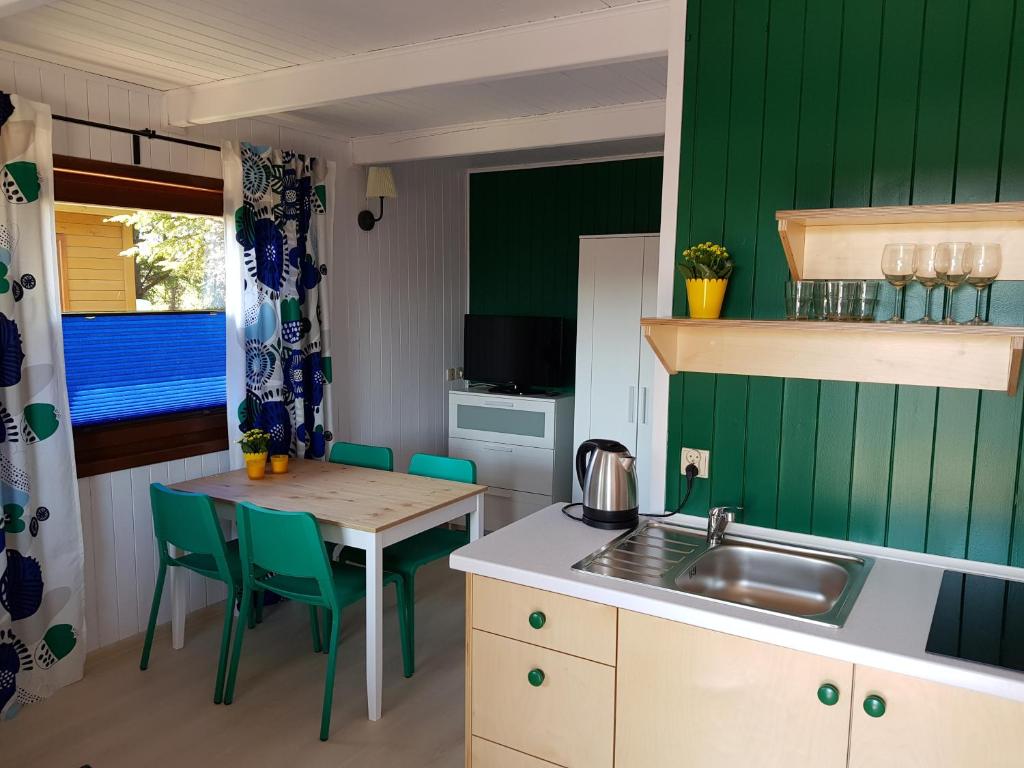 cocina con paredes verdes, mesa y fregadero en Draga, en Jastarnia