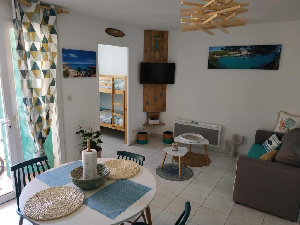 ein Wohnzimmer mit einem Tisch und einem Sofa in der Unterkunft Résidence Village Marin Catalan TORREILLES PLAGE in Torreilles