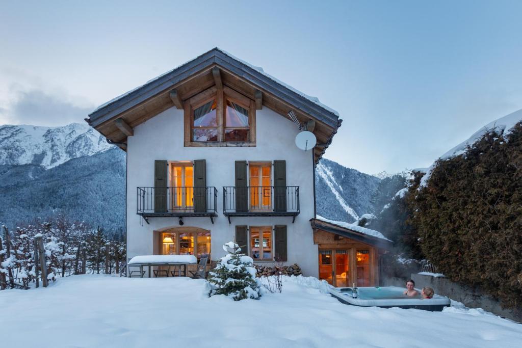 una casa nella neve con montagne sullo sfondo di Chalet les Tissourds a Chamonix-Mont-Blanc