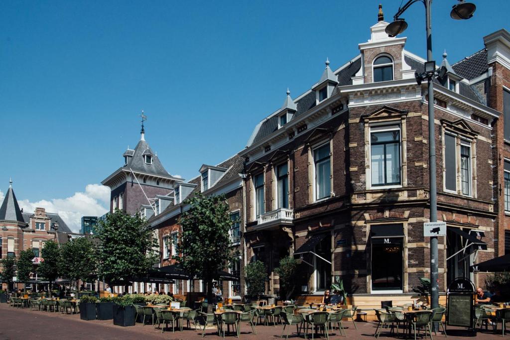 un edificio antiguo con mesas y sillas en una calle en Hotel ML en Haarlem