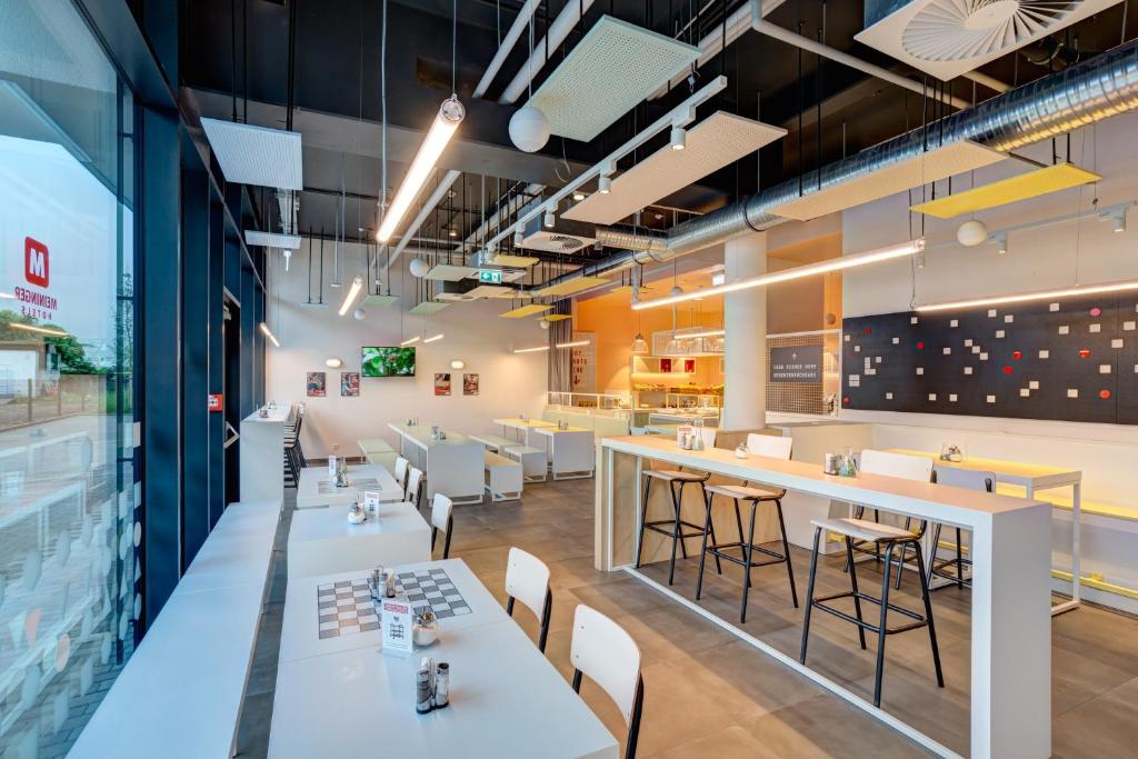 a restaurant with white tables and chairs and a bar at MEININGER Hotel Heidelberg Hauptbahnhof in Heidelberg