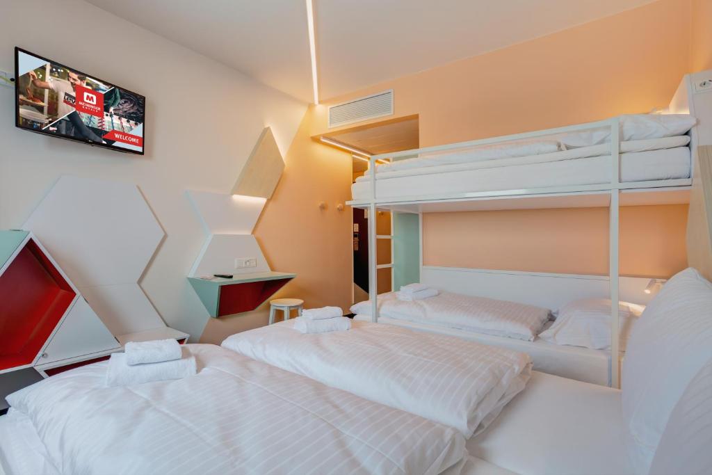 a bedroom with two bunk beds and a tv at MEININGER Hotel Heidelberg Hauptbahnhof in Heidelberg