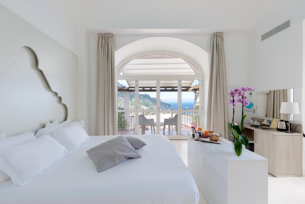 a white bedroom with a bed and a view of the ocean at Villa Piedimonte in Ravello