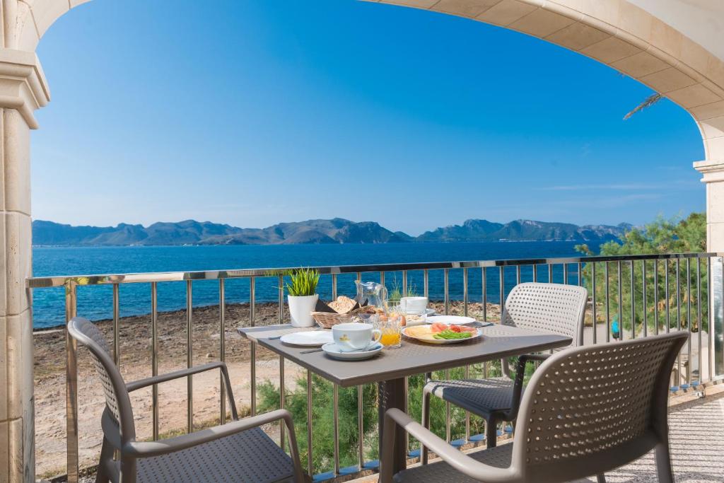a table and chairs on a balcony with a view of the water at Sunset Villa Nixe in Alcudia