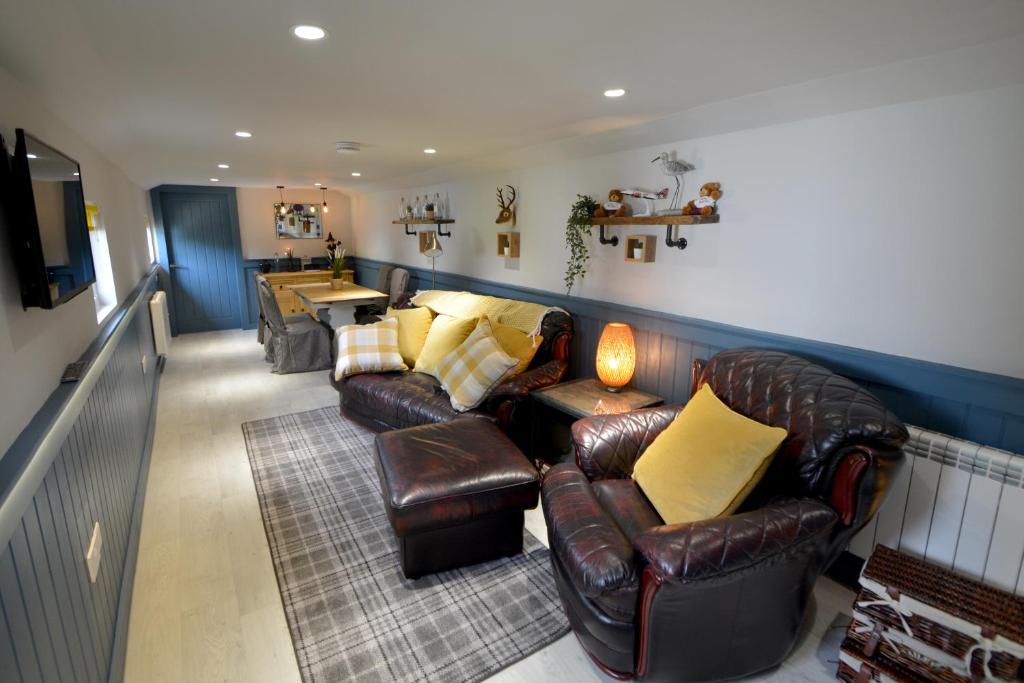 een woonkamer met lederen meubels en een televisie bij Craiglockhart Lodge in Edinburgh