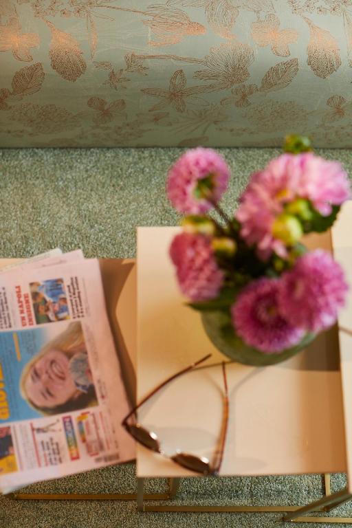a vase of flowers and a book and a pair of glasses at Hotel Metropol by Maier Privathotels in Munich