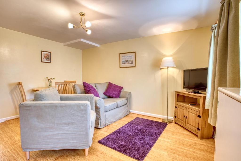 sala de estar con sofá y TV en Le Douit Farm Self Catering en St Martin Guernsey