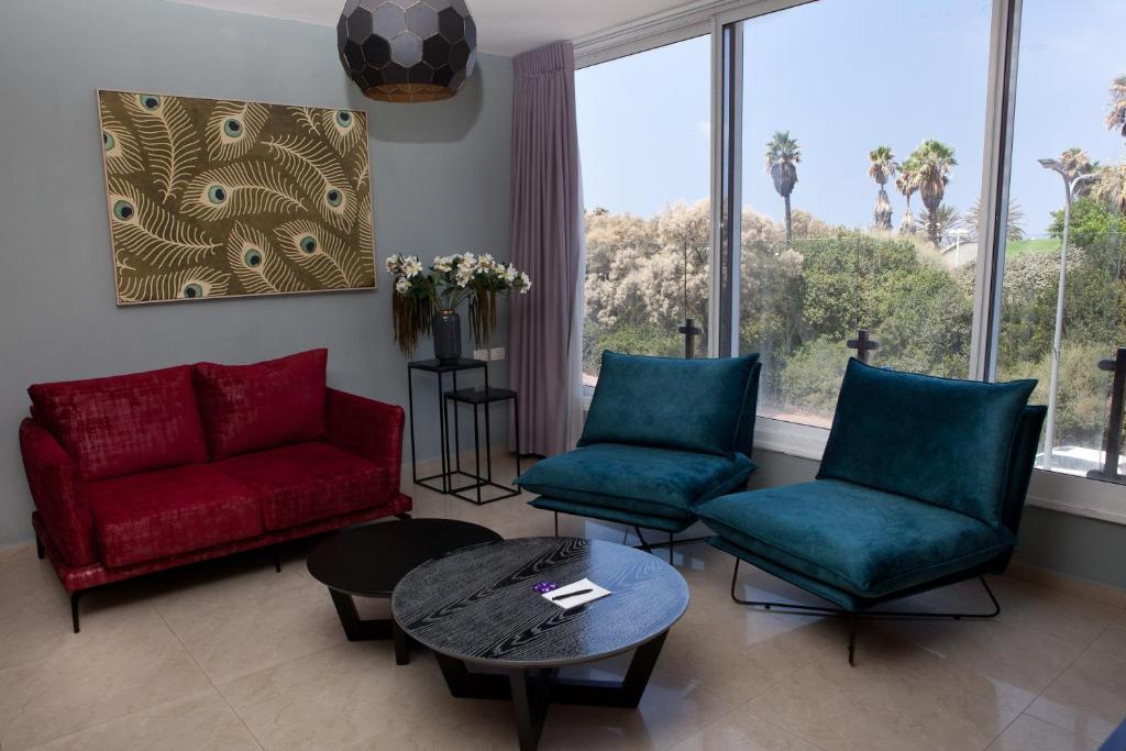 a living room with a red couch and two chairs at Liber Apartments BY RAPHAEL HOTELS in Tel Aviv