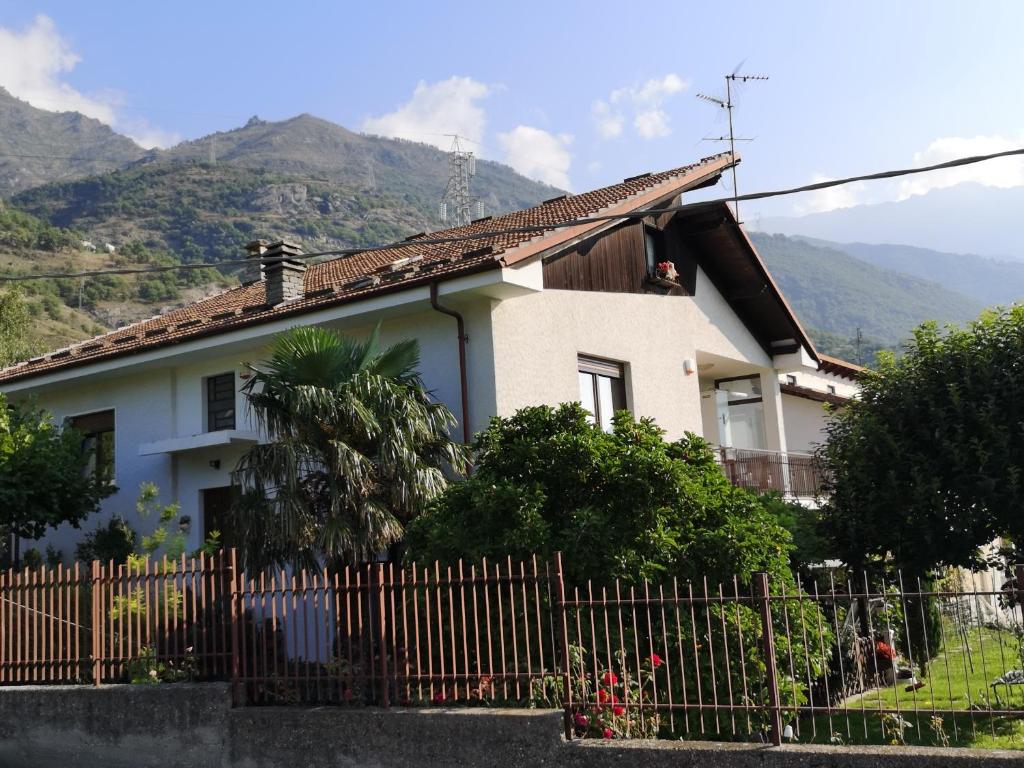 a house with a fence and mountains in the background at La Casa Dei Nonni in Bussoleno