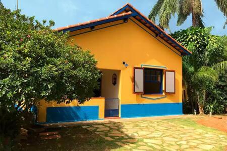 a small yellow and blue house with a tree at Quinta dos Paiva: horta natural e sossego in Monte Alegre do Sul