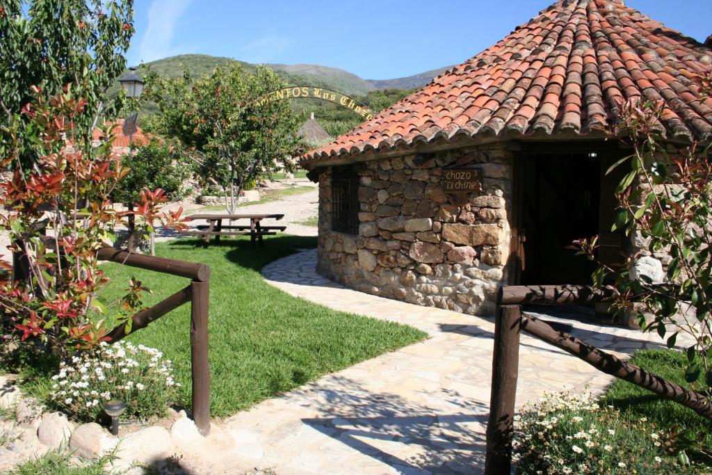 a small stone building with a bench in a garden at Complejo Rural Los Chozos Valle del Jerte in Jerte