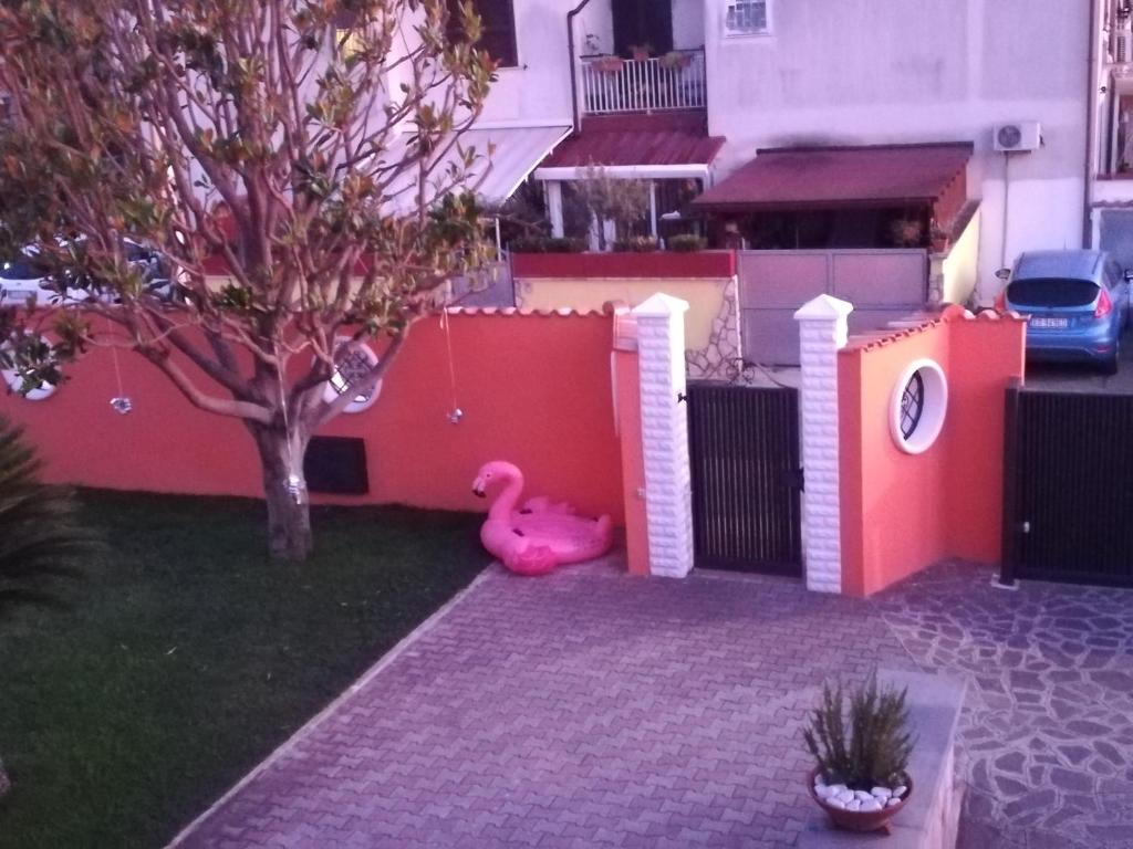 un'anatra giocattolo rosa seduta accanto a una recinzione di Orange Holiday Home a Torvaianica